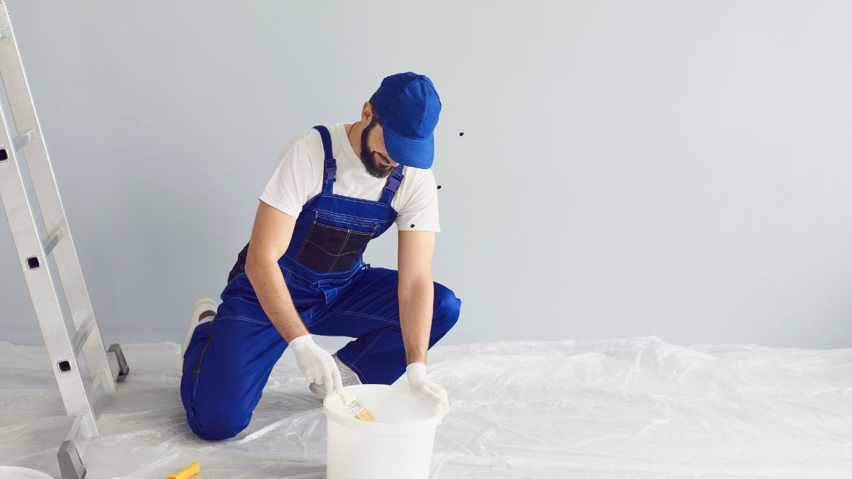 Pintor de obras aplicando tinta em estrutura predial, representando uma vaga urgente com ótimas condições de trabalho e benefícios. vagas urgentes